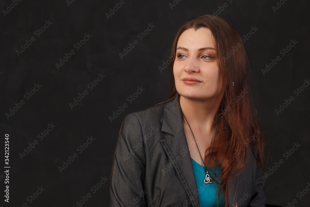 Young woman with dark hair womenwearing a blazer in a dark background Young woman with dark hair womenwearing a blazer in a dark background