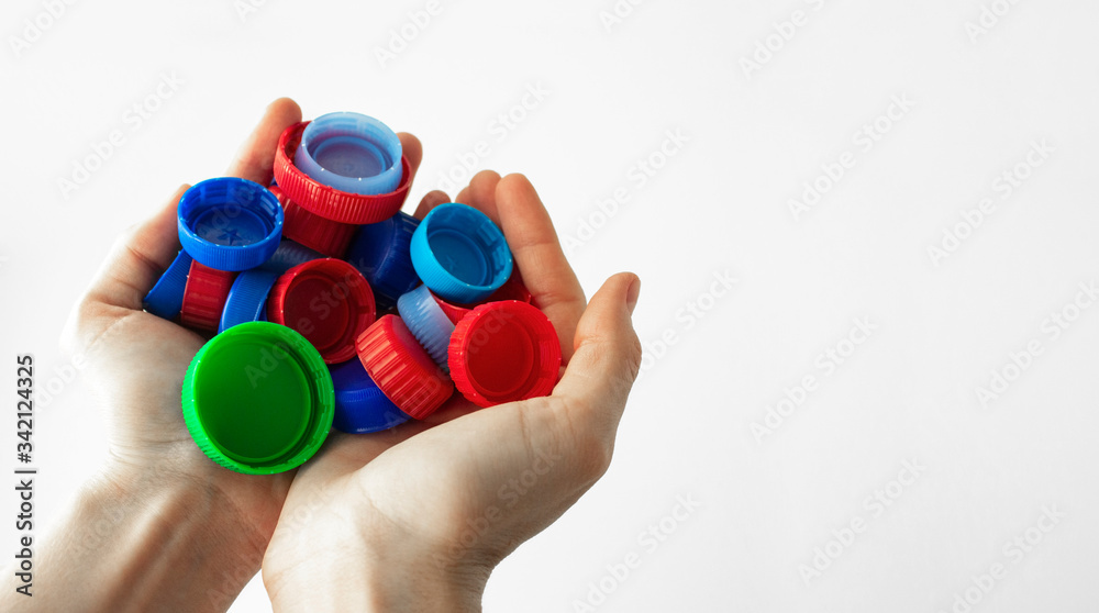 Handful of plastic caps in the hands. Concept of separate collection and recycling of plastic. Close-up. Sorting garbage. Horizontal banner template for website or social networks. Space for text. Handful of plastic caps in the hands. Concept of separate collection and recycling of plastic. Close-up. Sorting garbage. Horizontal banner template for website or social networks. Space for text.