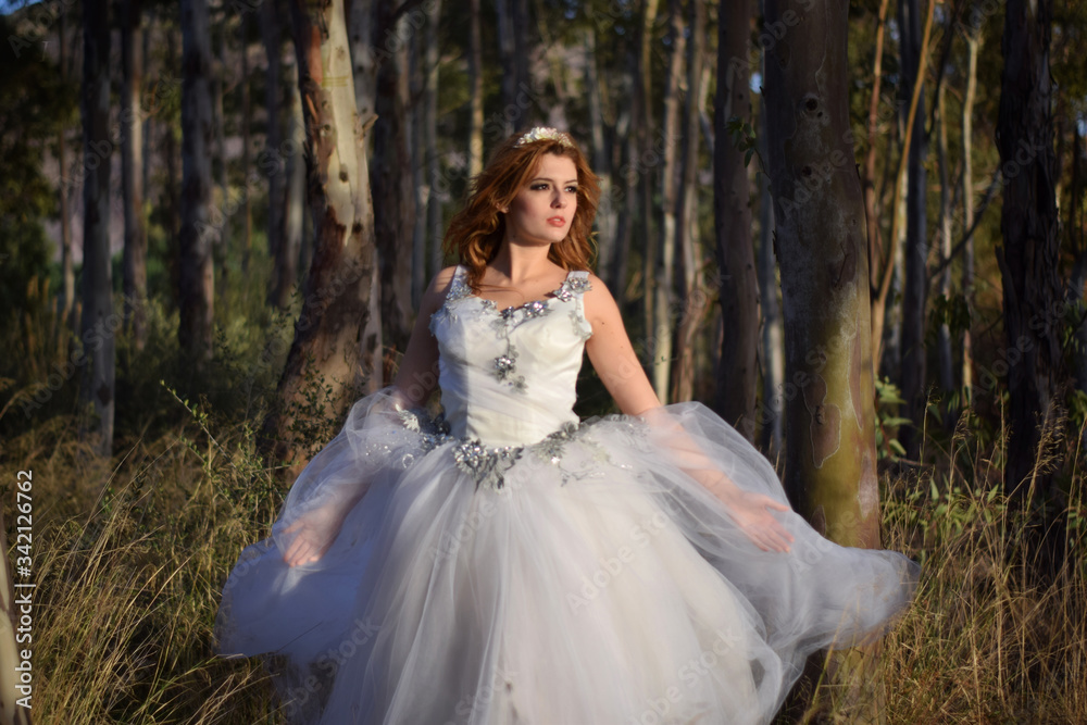 Beautiful girl with charming look with a white wedding dress in the forest