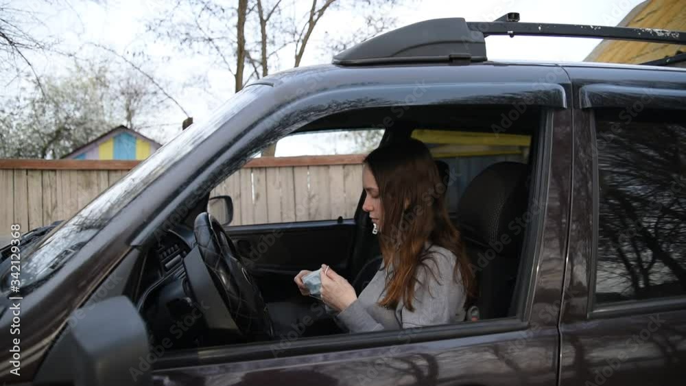 A female driver puts on a face mask and gloves in the car.Girl driver putting on medical mask and protective gloves in car before driving.Prevention of infection