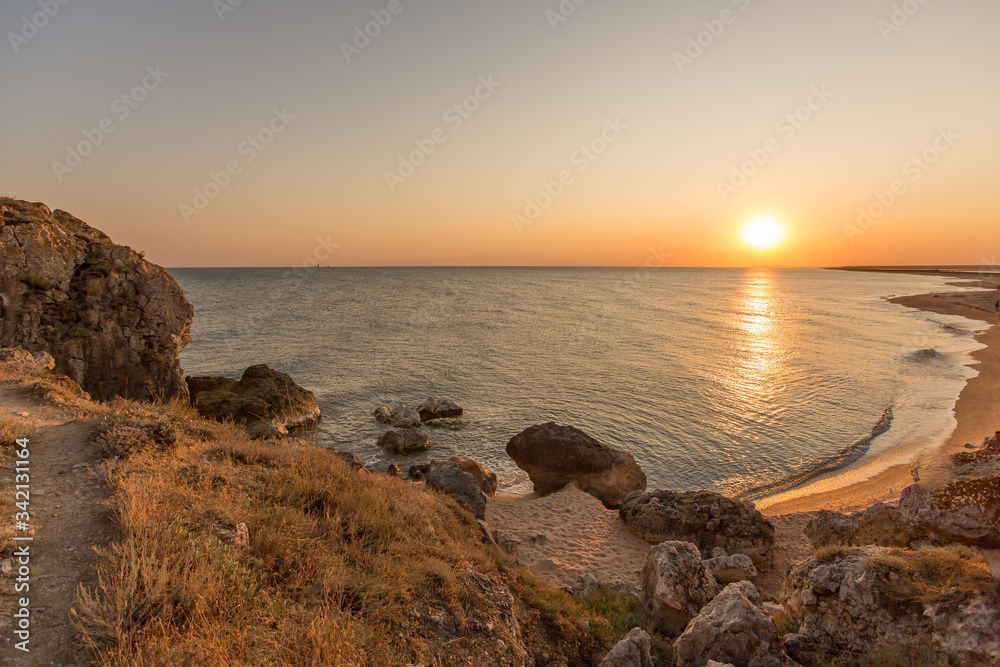 Incredibly beautiful sunset on the sea with pink and red sky, sun, and clean sand.