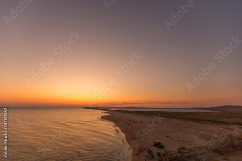 Incredibly beautiful sunset on the sea with pink and red sky, sun, and clean sand.