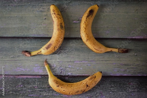 Ripe yellow bananas on a wooden green background close up. Banana smile. View from above. Vegetarian concept