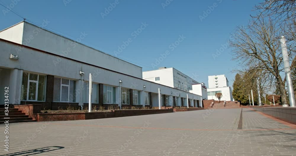 Empty city street during quarantine. Pan left view of empty pavement and white buildings against cloudless blue sky on sunny day on city street during COVID 19 quarantine Empty city street during quarantine. Pan left view of empty pavement and white buildings against cloudless blue sky on sunny day on city street during COVID 19 quarantine