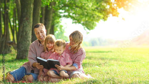 Canvas Print young family reading the Bible in nature