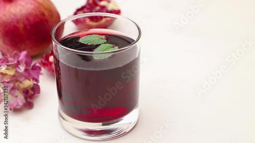 Wallpaper Mural Male hand puts mint leaves into a drinking glass of pomegranate juice on white background. Side view, close up, copy space. Torontodigital.ca