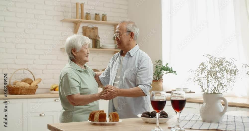 Cute senior asian couple are celebrating their anniversary, drinking wine, listening to music and dancing in their kitchen, relaxing after retirement - pension, old couple in love 4k footage Cute senior asian couple are celebrating their anniversary, drinking wine, listening to music and dancing in their kitchen, relaxing after retirement - pension, old couple in love 4k footage