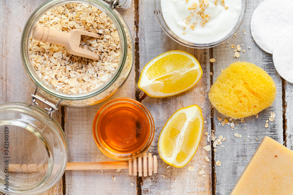 Concept of natural organic ingredients in cosmetology and gentle home treatment during quarantine. Do it yourselft. Handmade mask with honey, yogurt, oats, lemon. Wooden background. Flat lay top view Concept of natural organic ingredients in cosmetology and gentle home treatment during quarantine. Do it yourselft. Handmade mask with honey, yogurt, oats, lemon. Wooden background. Flat lay top view