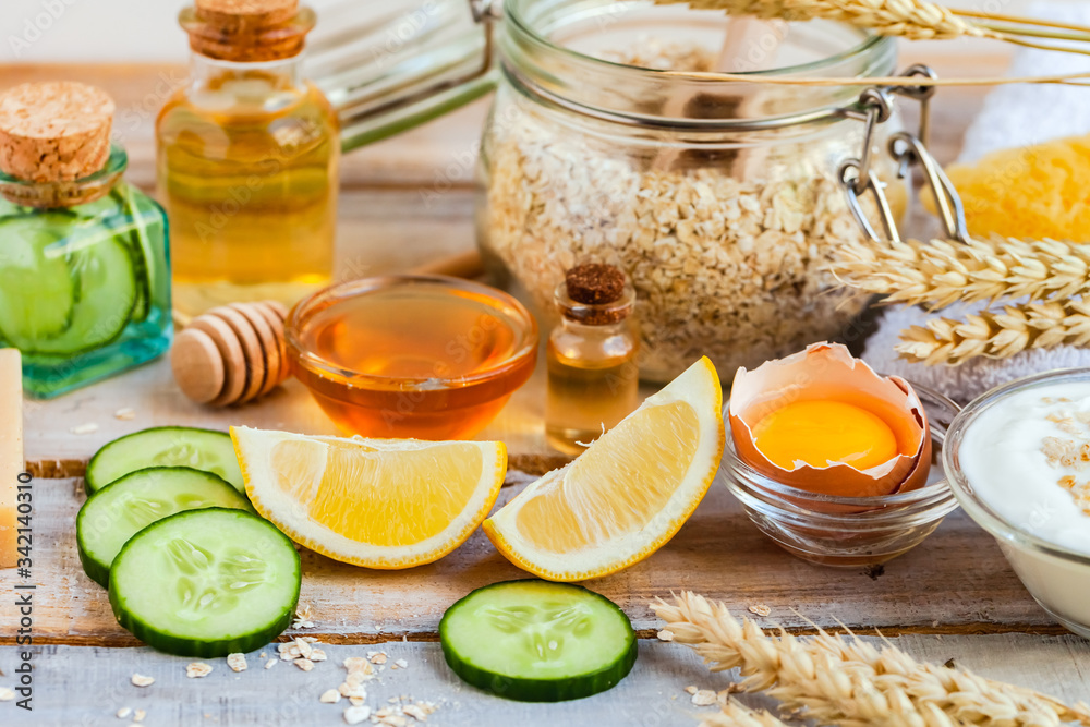 Concept of natural organic ingredients in cosmetology, home treatment during quarantine. Do it yourselft. Handmade mask with honey, egg, oat, lemon, cucumber, essential oils. Wooden background
