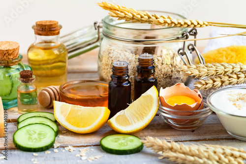 Concept of natural organic ingredients in cosmetology, home treatment during quarantine. Do it yourselft. Handmade mask with honey, egg, oat, lemon, cucumber, essential oils. Wooden background photo