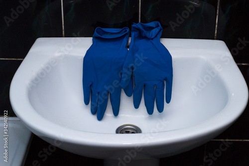 Blue rubber gloves on the sink. Bathroom cleaning.