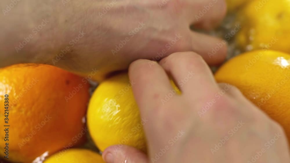 Close up of male hands washing fresh fruits. Preparing fruit before eating. Lemons, grapefruits and oranges. Healthy lifestyle. Protection against coronavirus. Close up of male hands washing fresh fruits. Preparing fruit before eating. Lemons, grapefruits and oranges. Healthy lifestyle. Protection against coronavirus.