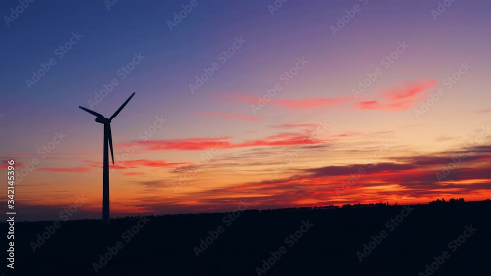 Sunset above the windmills silhouette on the field Sunset above the windmills silhouette on the field