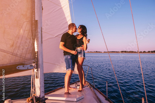 Happy couple in love on sailboat kissing when standing under sail on yacht © VlaDee