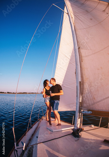 Happy couple in love on sailboat kissing when standing under sail on yacht © VlaDee