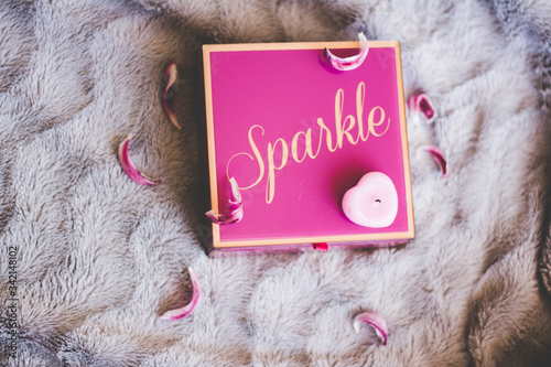 bright pink jewelry box with dry flower petals heart shaped pink candle and grey background