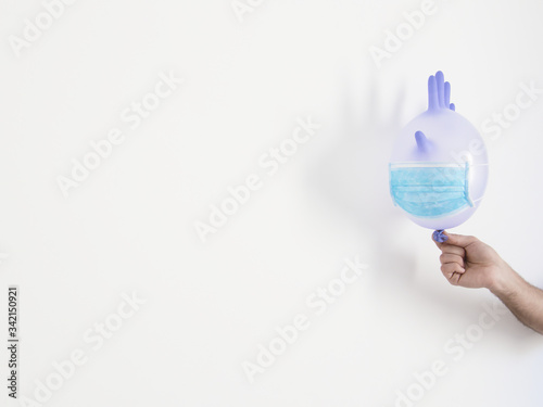 Hand holding a disposable glove inflated as a balloon with a face mask. Concept of coronavirus, hygienic education for children