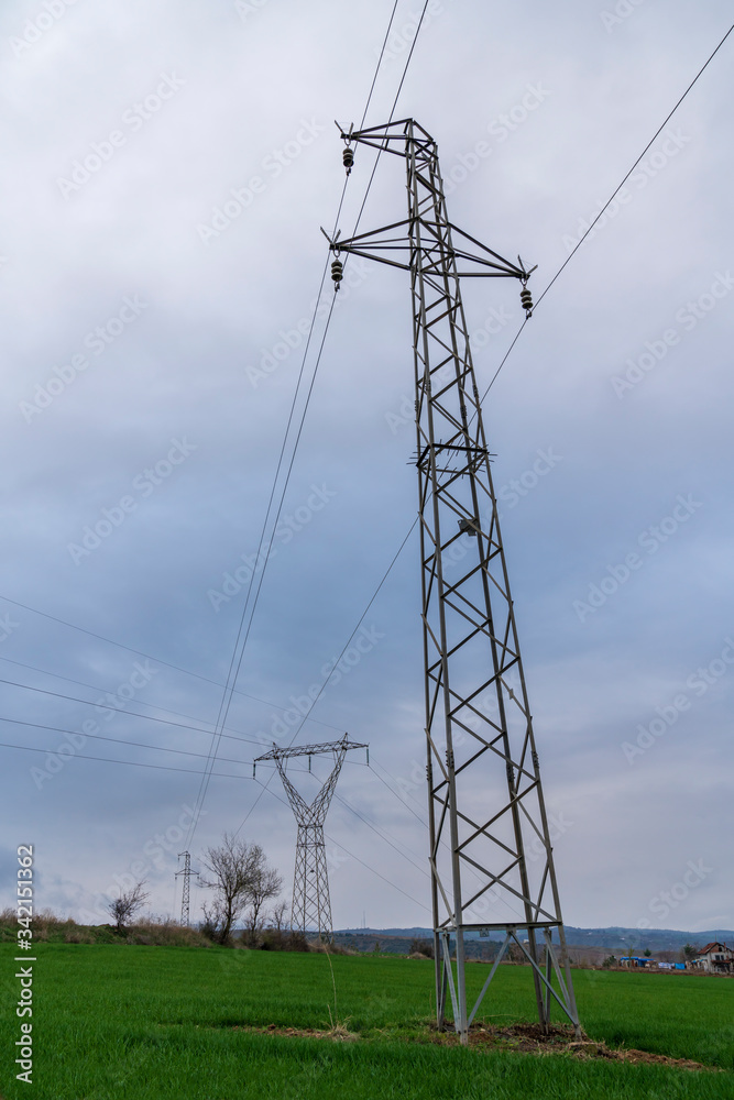 High-voltage lines in a rural area, metal electric cable poles used in the field 