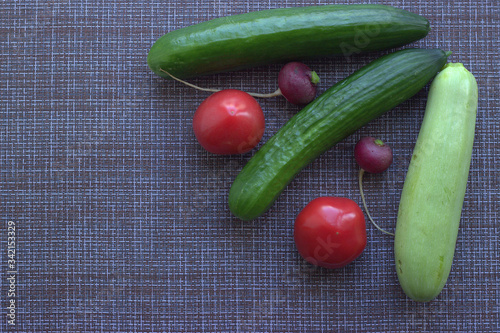 
Cucumbers, radishes pink and red tomatoes on the kitchen table. View from above