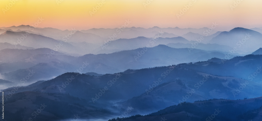 silhouettes of foggy mountains. picturesque mountain peaks at sunrise.