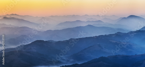 silhouettes of foggy mountains. picturesque mountain peaks at sunrise. © sergnester