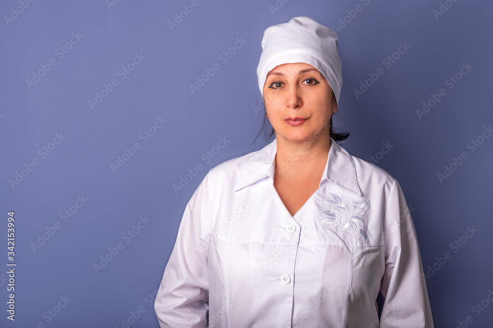 A female doctor in a white uniform smiling on blue grey background. A female doctor in a white uniform smiling on blue grey background.