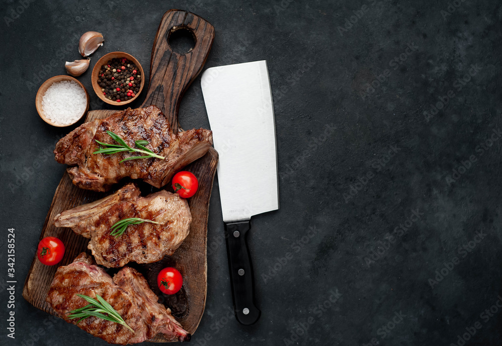 three grilled steaks with beef spices on a cutting board on a stone background with copy space for your text three grilled steaks with beef spices on a cutting board on a stone background with copy space for your text
