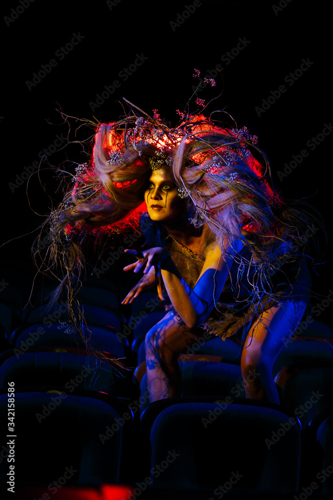 Fototapeta premium The girl who plays the role of a Ghost or spirit in the theater is sitting between the rows of chairs