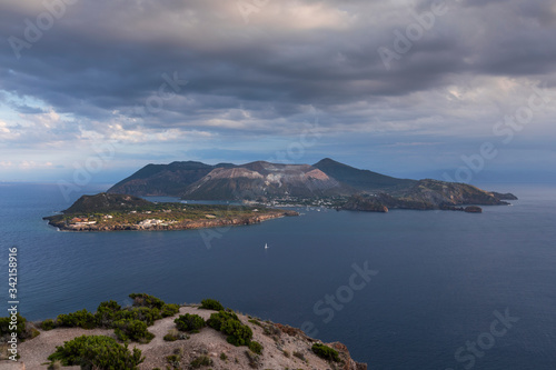 View to volcano island Vulcano, Lipari coast in the front, with dramatic clouds in the sky, Sicily Italy.