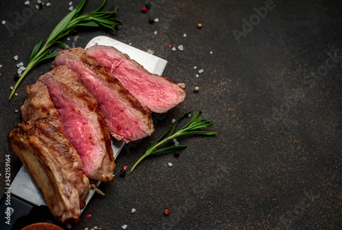 grilled beef steak with spices on a knife, stone background with copy space for your text