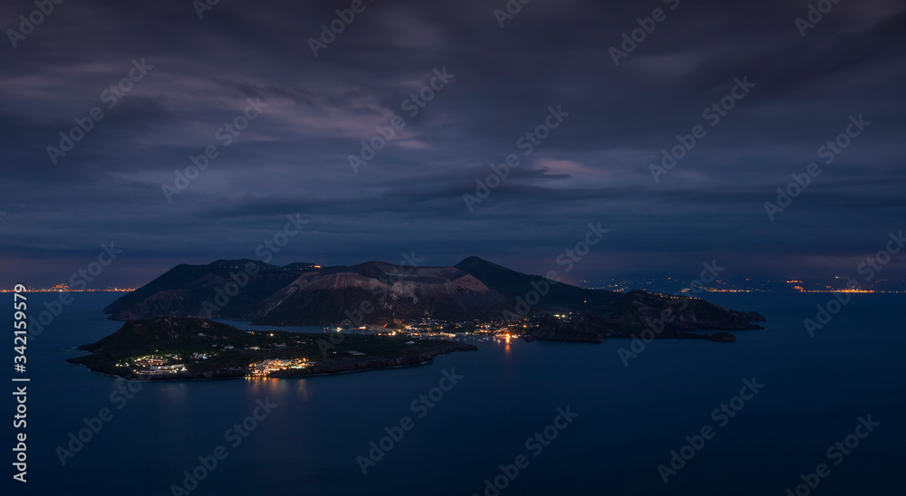 Panorama view to volcano island Vulcano, with dramatic clouds in the sky during night, Sicily Italy.