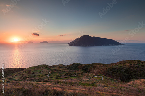 Coast with grass fields of Lipari with view to volcano islands Salina  Alicudi  Filicudi during sunset  Sicily Italy.