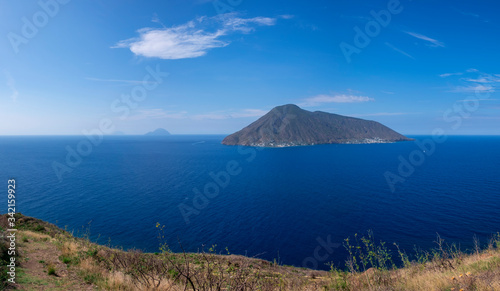Coast with grass fields of Lipari with view to volcano islands Salina, Alicudi, Filicudi during blue sky day, Sicily Italy.