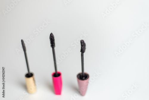 Various mascara brushes on a blue pastel background. The concept of choosing makeup products