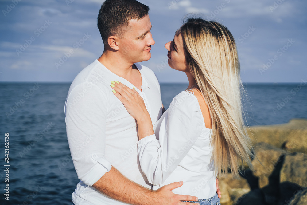 Loving couple having fun - they laugh, hug each other and enjoy warm summer evening. A romantic couple stands on the seashore in the golden rays of the sun and spends time together, enjoying deserts Loving couple having fun - they laugh, hug each other and enjoy warm summer evening. A romantic couple stands on the seashore in the golden rays of the sun and spends time together, enjoying deserts