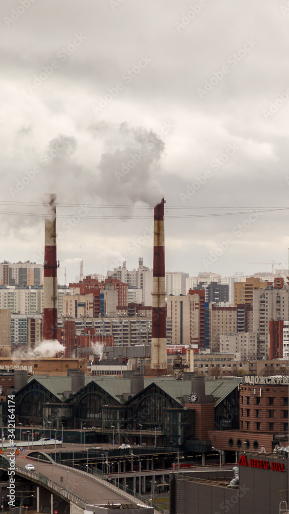 Environmental and air pollution, ecological problems concept. Smoke from factory chimneys against a gray cloudy sky. Urban landscape.