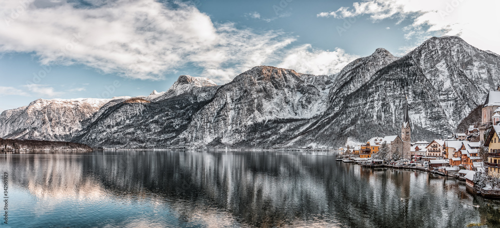 Panorama view of snowy village Hallstatt by lake at foot of snow mountain with clear sky in winter in Austria