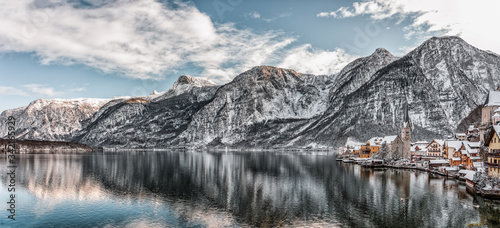 Panorama view of snowy village Hallstatt by lake at foot of snow mountain with clear sky in winter in Austria