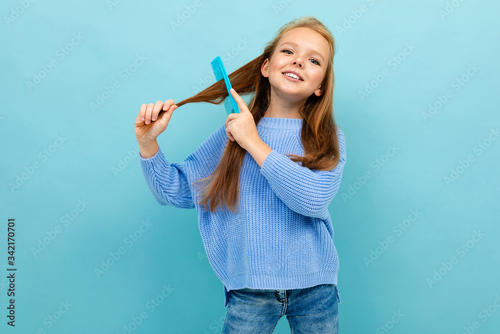 attractive european girl combing her hair on a blue wall attractive european girl combing her hair on a blue wall