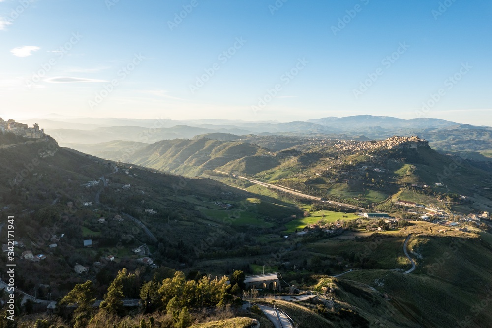 Wide-angle shot of Sicilian landscape with the city of Calascibetta at nice sunset with shadow of Enna city