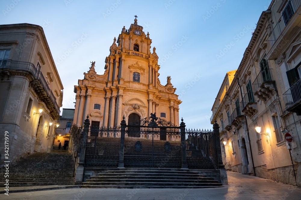 Church of Saint George (Duomo di San Giorgio) in historical town Ragusa, Sicily, Italy at early evening with blue sky and street lights