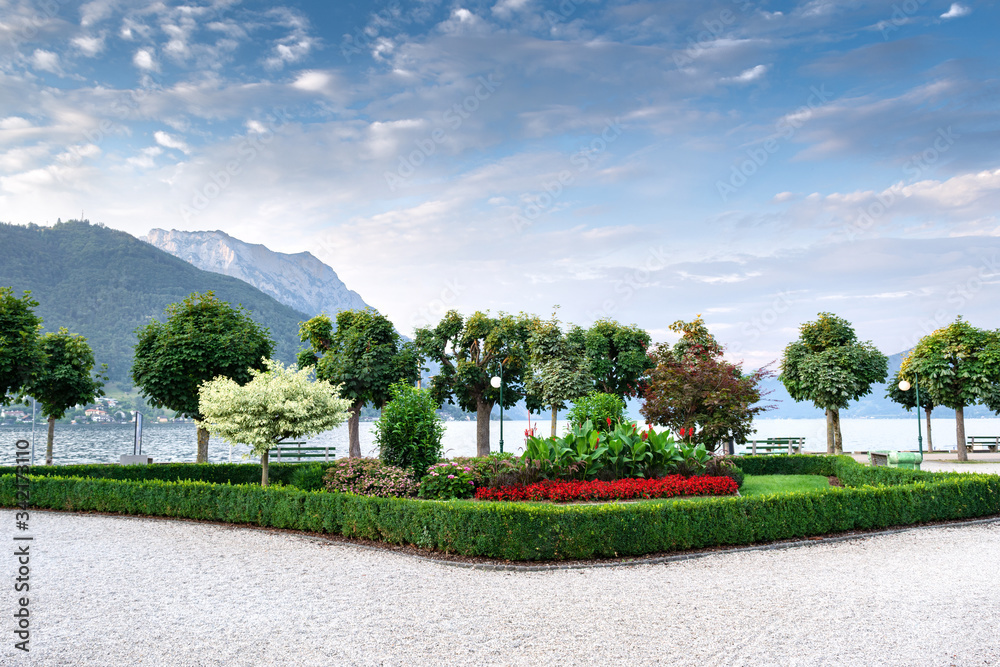 View of the embankment on the lake against the backdrop of mountains and blue sky with beautiful clouds. Concept landscape, landscape design.