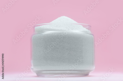 Sugar in a glass bowl on a pink background. photo