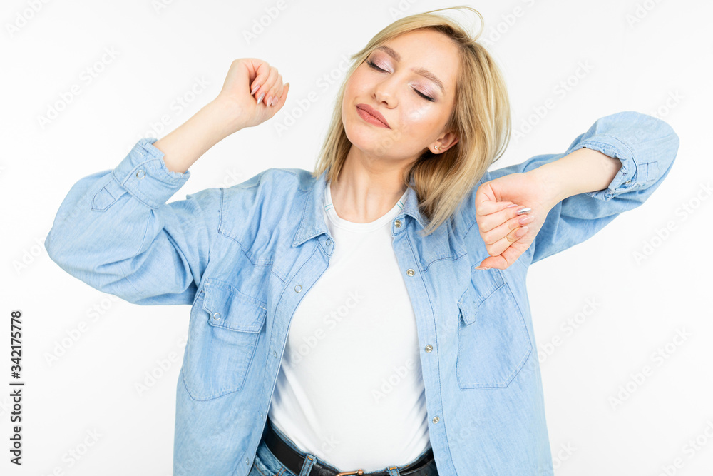 fashionable blonde girl in a denim blue shirt is dancing energetically on a white studio background fashionable blonde girl in a denim blue shirt is dancing energetically on a white studio background