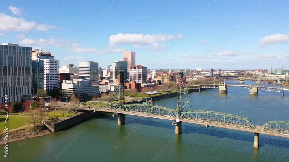Aerial through Hawthorne Bridge in Portland Oregon over Willamette River reveals downtown business district.
