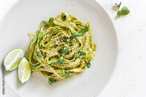 Green vegan spinach tagliatelle with sunflower seeds microgreens and sesame seeds   photo