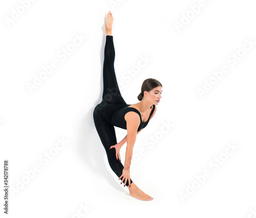 Beautiful athletic young girl gymnast in sportswear, training, element of gymnastics, performs exercises on a white background. Sports motivation, stretching, banner for advertising.