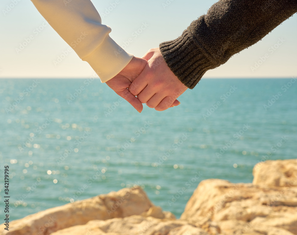 Man and woman are keeping together their hands with sea, horizon and stones on a background. Love concept. Man and woman are keeping together their hands with sea, horizon and stones on a background. Love concept.