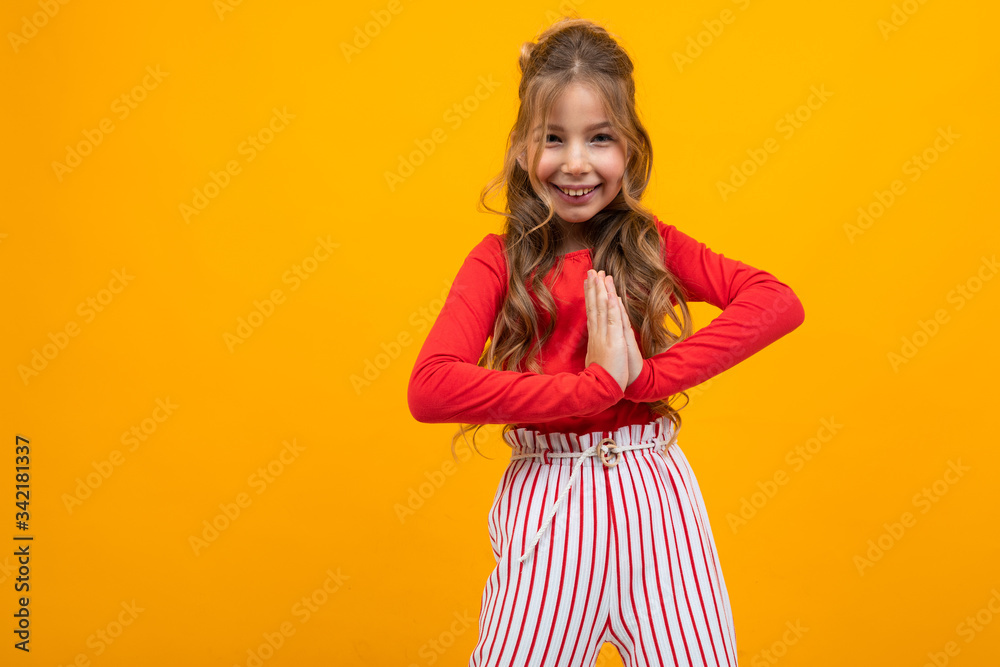 charming teenager girl in a red blouse and striped trousers shows emotions on a yellow background with copy space