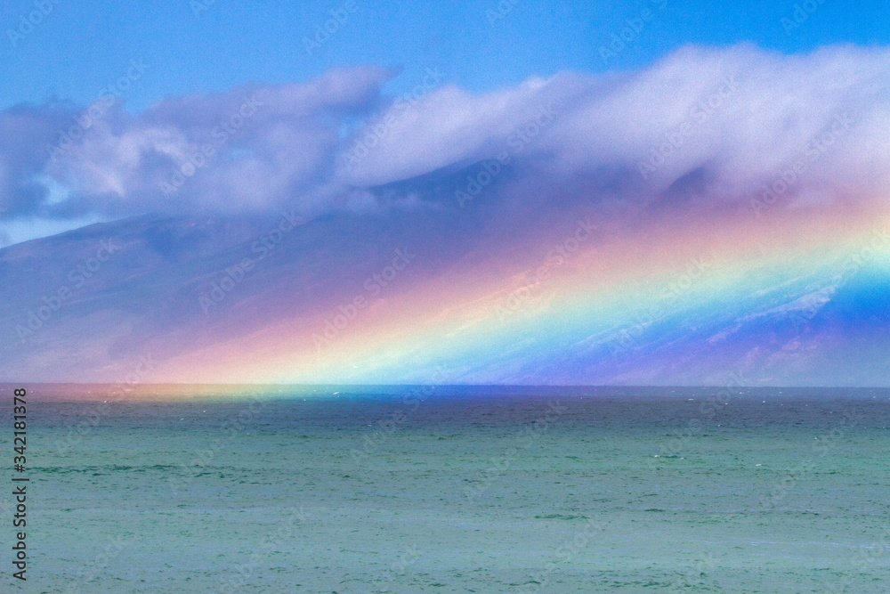 Electric rainbow hovering over the ocean on Maui.